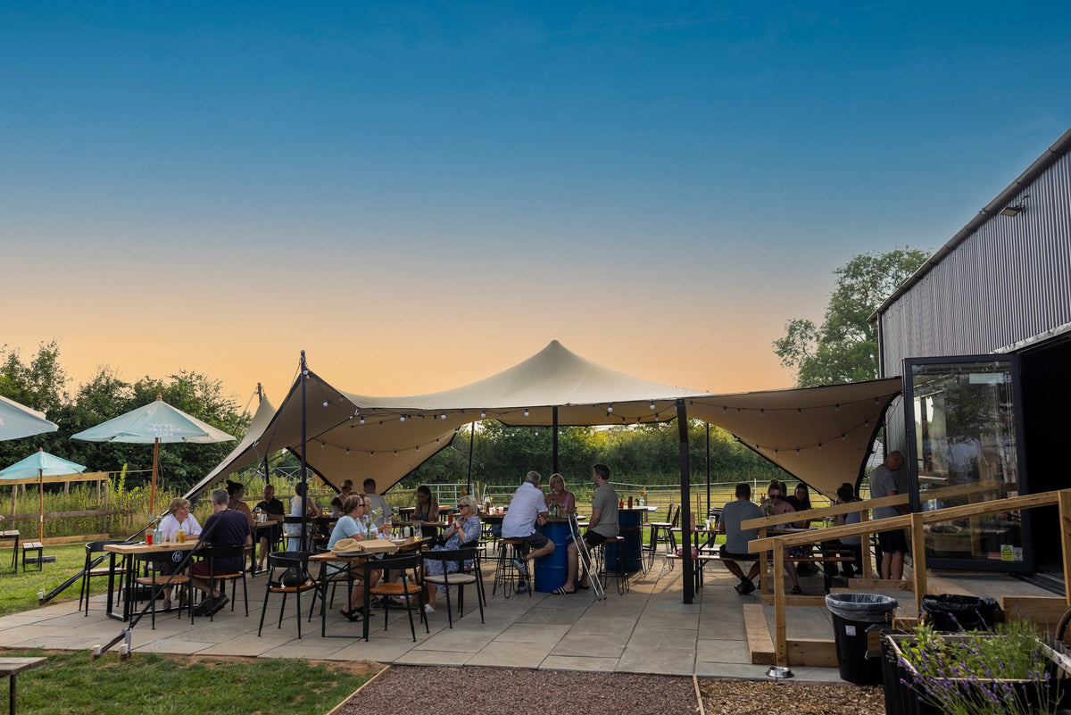 The covered terrace at Silver Circle Distillery at dusk, set with tables for a group
