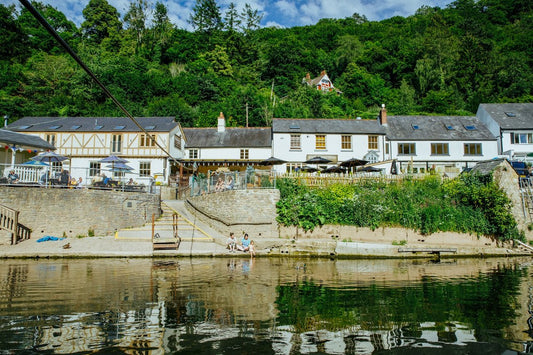 The Saracens Head Inn seen from the River Wye at Symonds Yat East, with its riverside terrace and wooded hillside behind