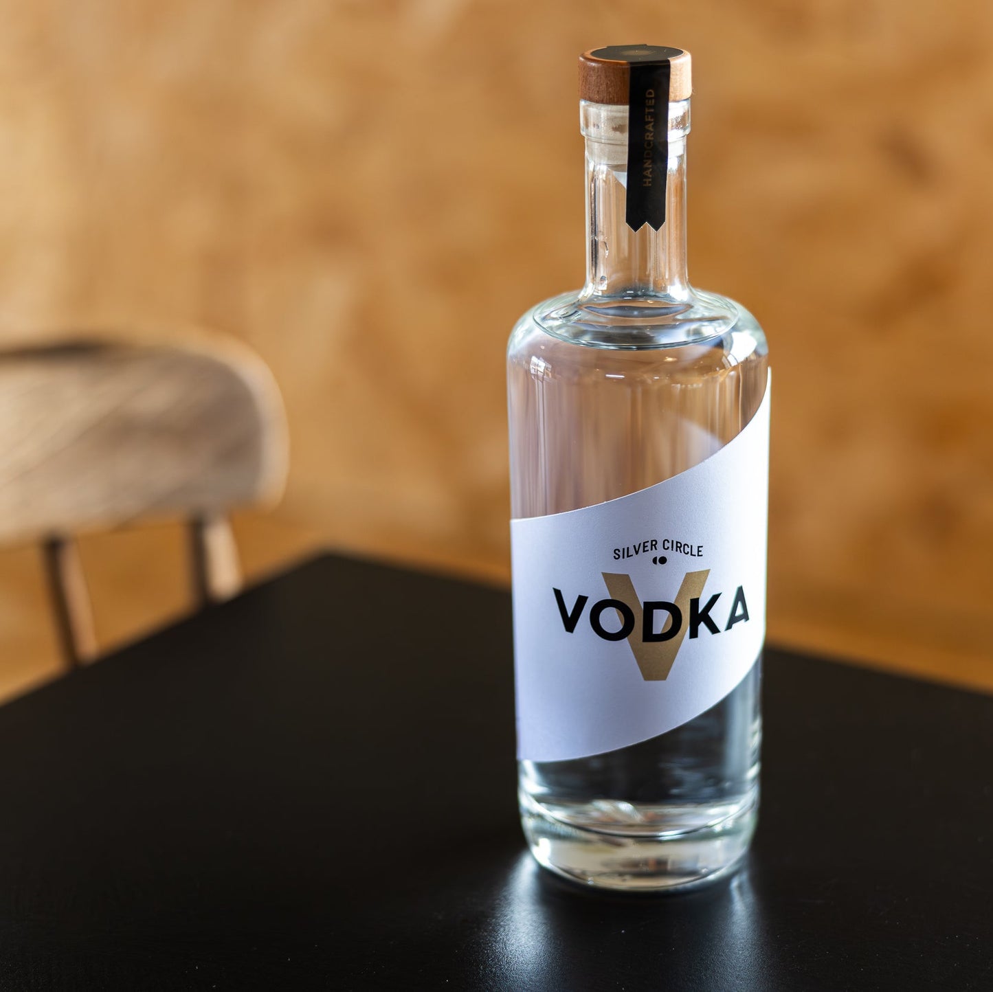 Bottle of Silver Circle Vodka on a dark surface with a blurred wooden background

